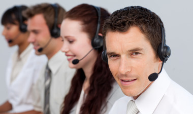 Attractive man working with his team in a call center with a headset on